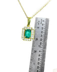 0.75 ct. GIA certified F1 Colombian emerald pendant in 18k yellow gold with diamond halo, next to a ruler.