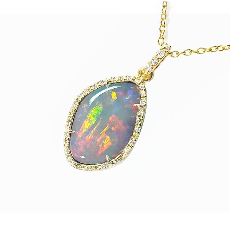 Opal pendant necklace with gold chain on a left side profile view.