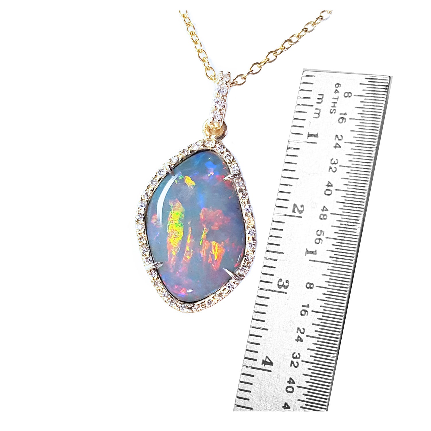 Opal pendant necklace with a ruler for scale on a white background.