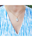 Necklace with a natural opal pendant worn by a woman in a blue and white patterned top.