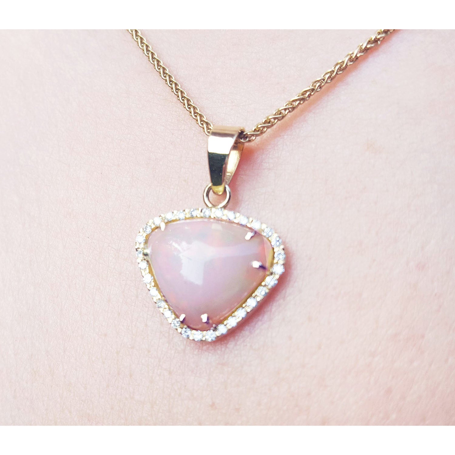 Heart-shaped pink gemstone pendant on a gold chain against a light pink skin background.