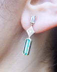Close-up of a person wearing a baguette cut emerald earring.