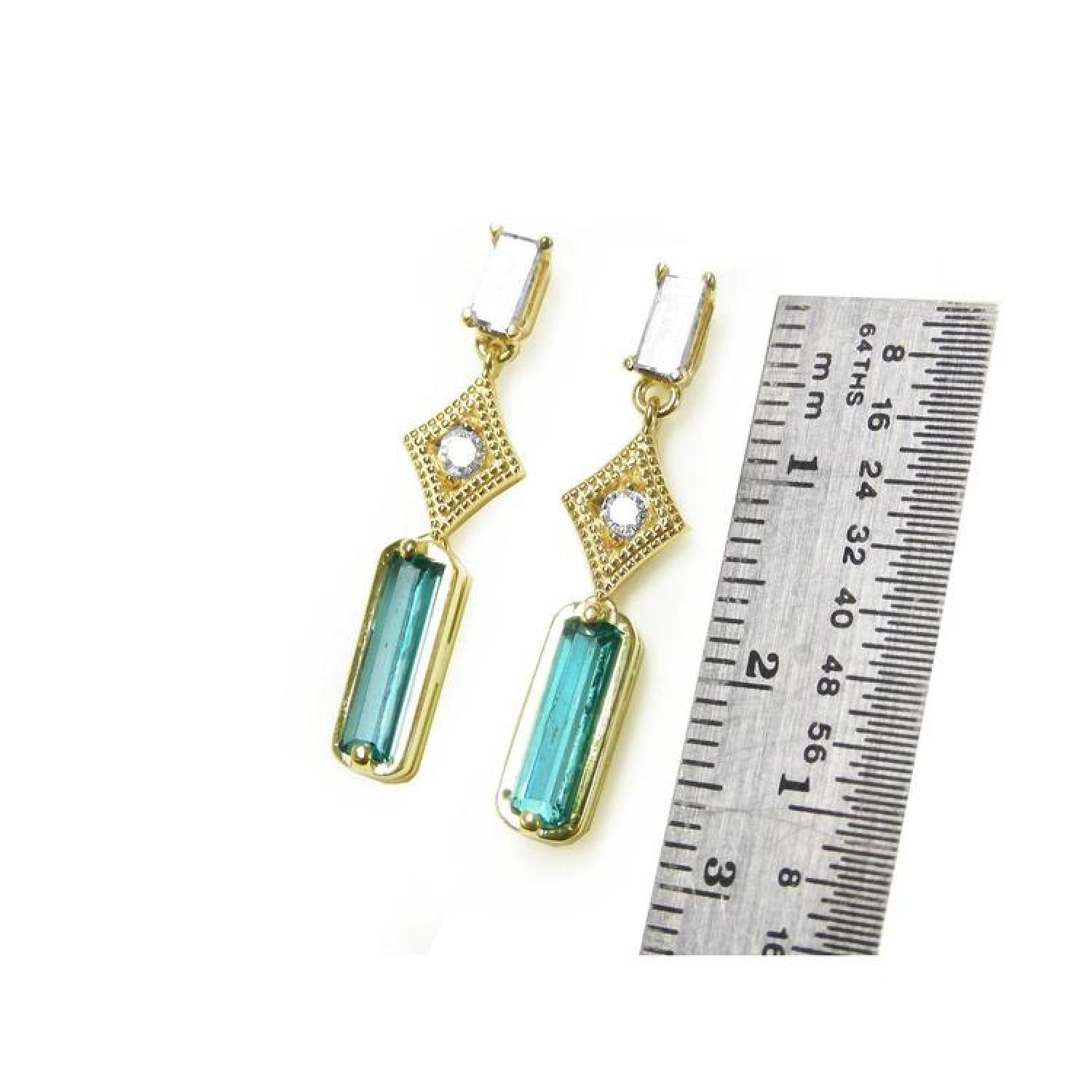 14K gold baguette emerald earrings with clear top stones and diamond accents, next to a ruler.