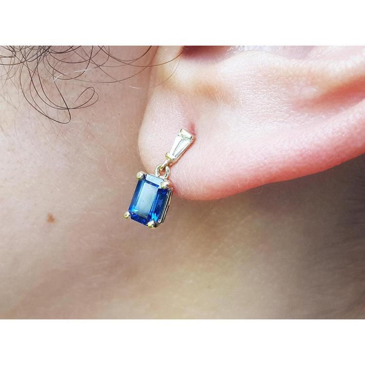 14K yellow gold dangling earrings with emerald cut blue sapphires and tapered baguette diamonds.