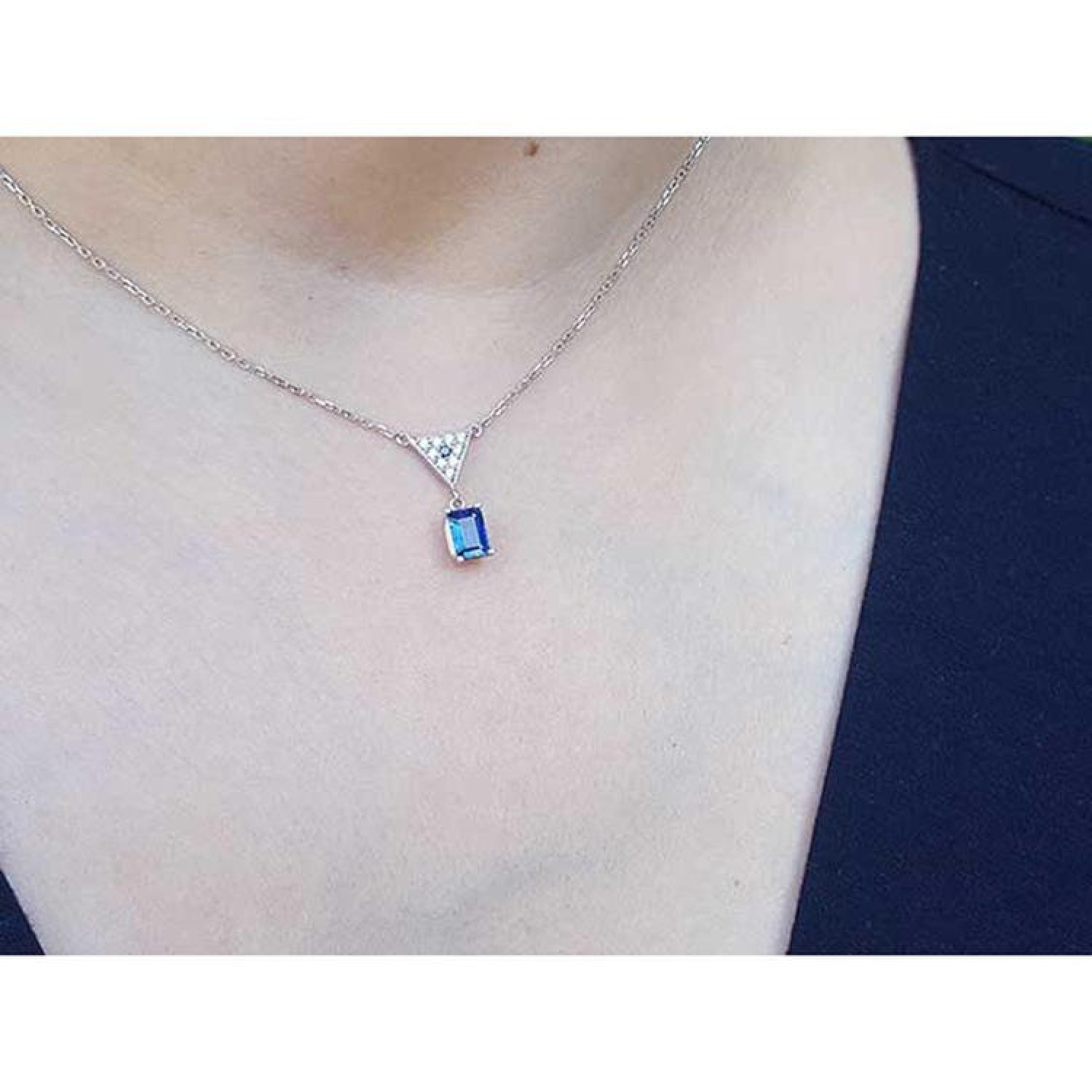 14K white gold necklace with a dangling emerald-cut blue sapphire and pave diamond trillion pendant.