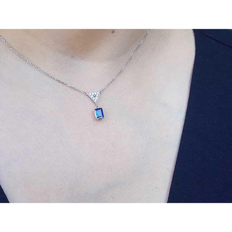 14K white gold necklace with a dangling emerald-cut blue sapphire and pave diamond trillion pendant.