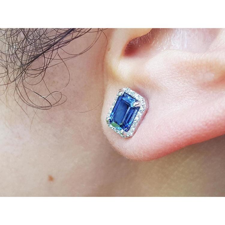Blue sapphire earring worn on an ear with a close-up view.