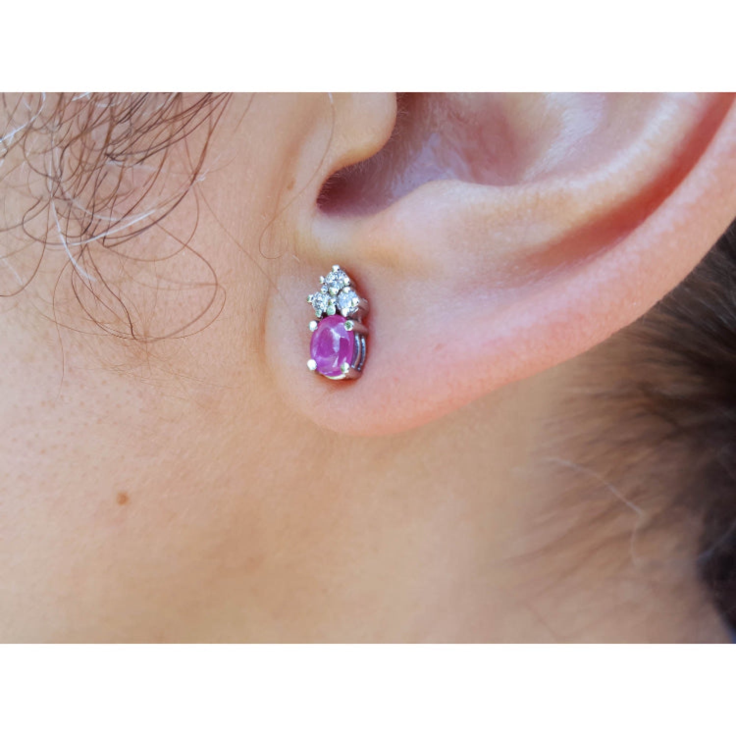 Close-up of an ear wearing a pink cabochon pink sapphire earring in 14k white gold.