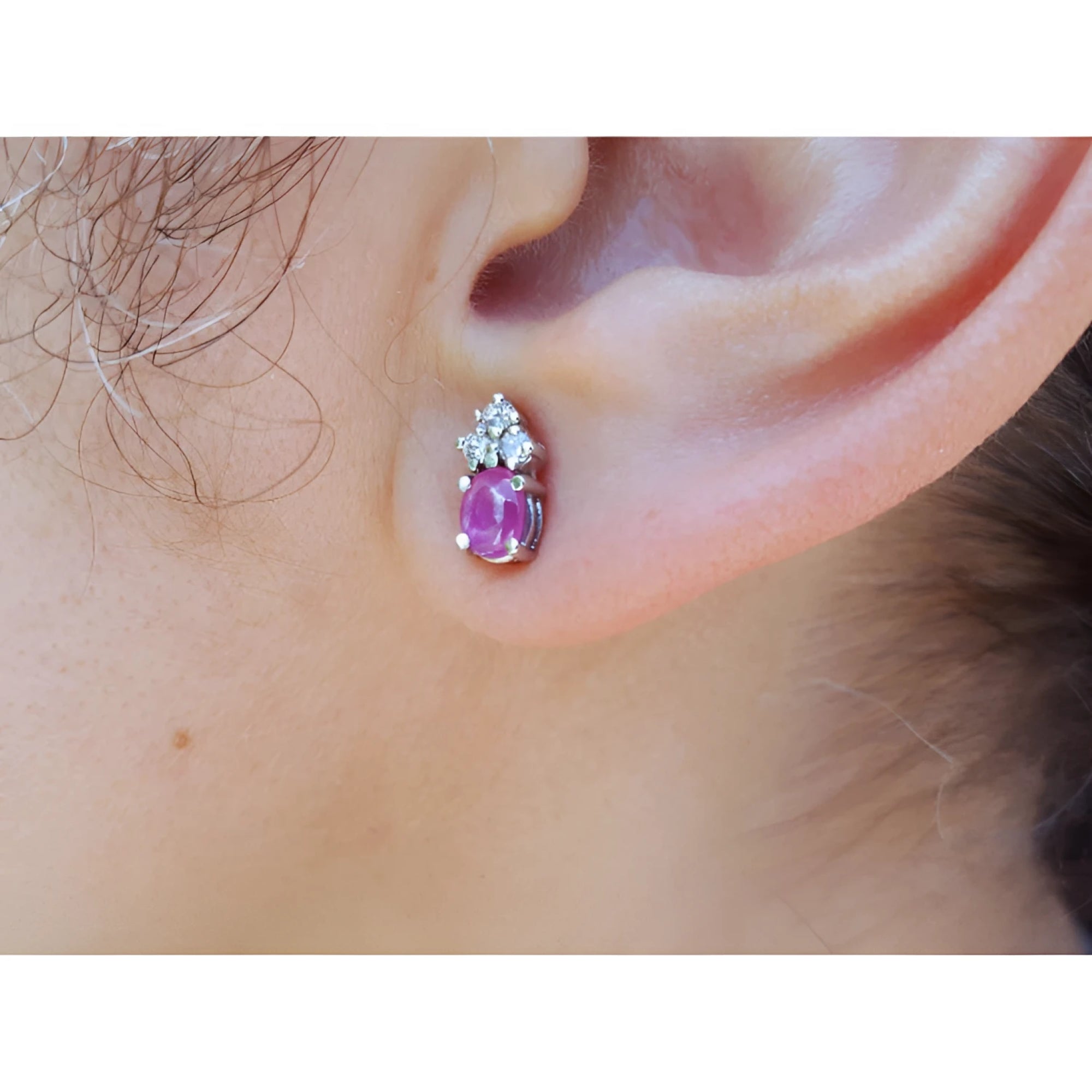 Close-up of an ear wearing a pink cabochon pink sapphire earring in 14k white gold.
