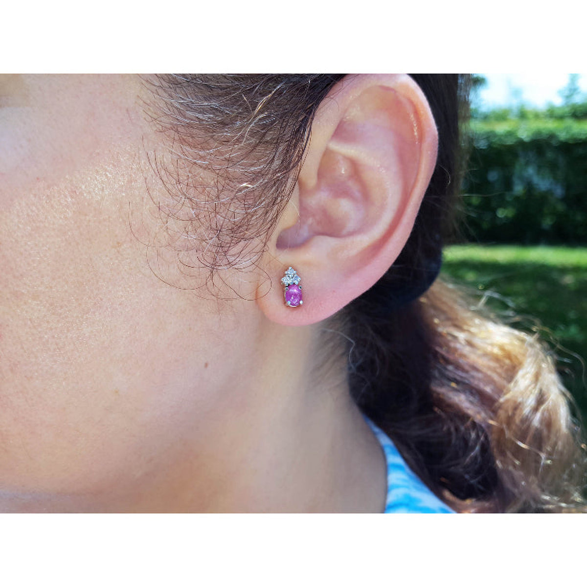 Close-up of a woman wearing a pink sapphire and diamonds stud earring.