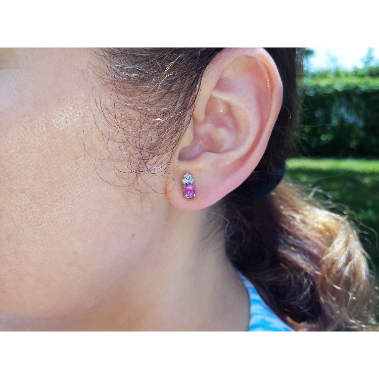 Close-up of a woman wearing a pink sapphire and diamonds stud earring.