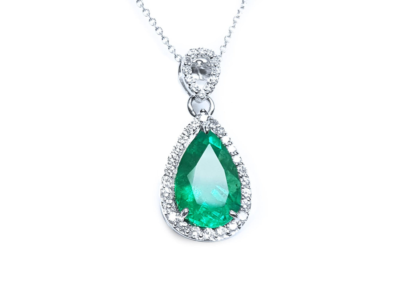 Teardrop-shaped emerald pendant into a halo diamond made in 18k white gold topside view.