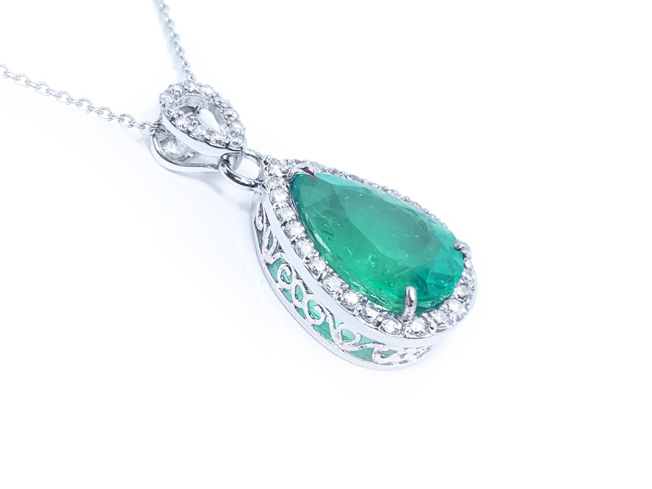 Emerald green teardrop pendant with white gold chain on a right side position topside and gallery visibles.