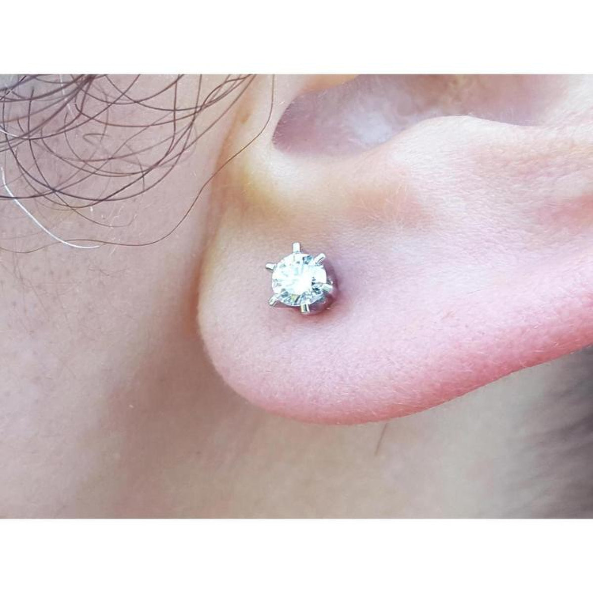 A woman's earlobe wearing a natural diamond stud earring in 14k white gold.