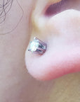 Close up of a 14k white gold diamond stud earring screw back on earlobe.