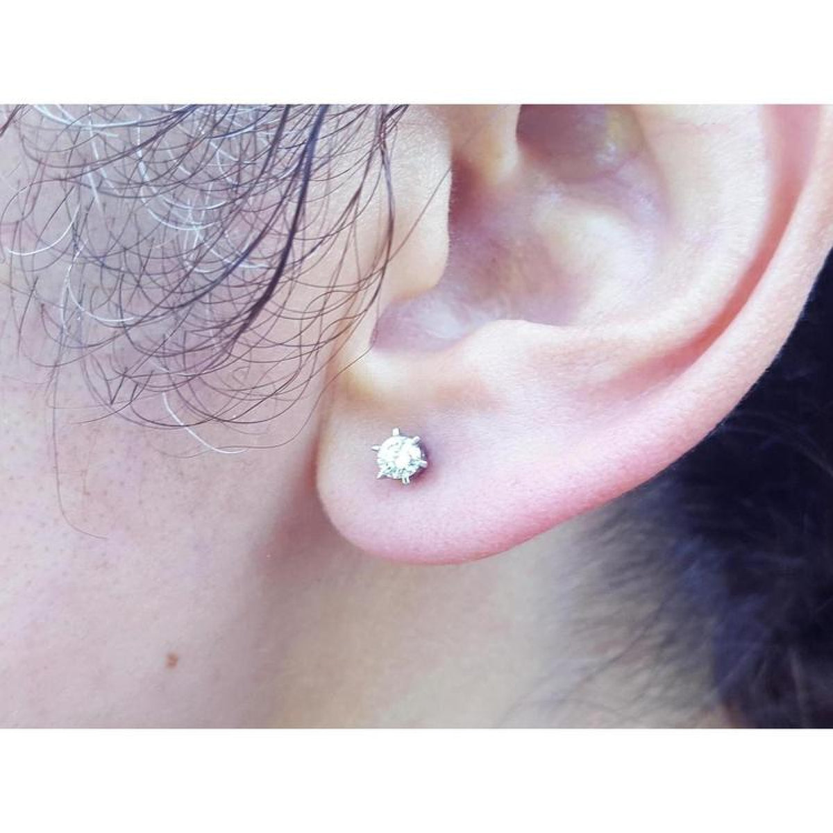 14K white gold natural diamond stud earring with six-prong setting and screw back worn on an ear.