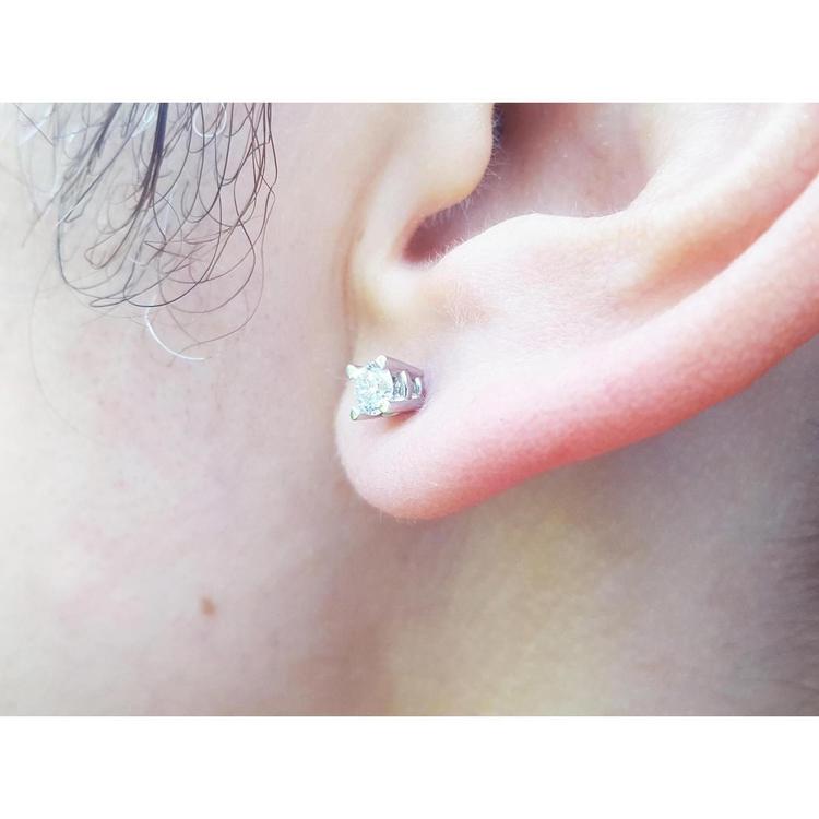 An earlobe wearing a natural diamond stud earring in 14k white gold.
