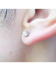 An earlobe wearing a natural diamond stud earring in 14k white gold.