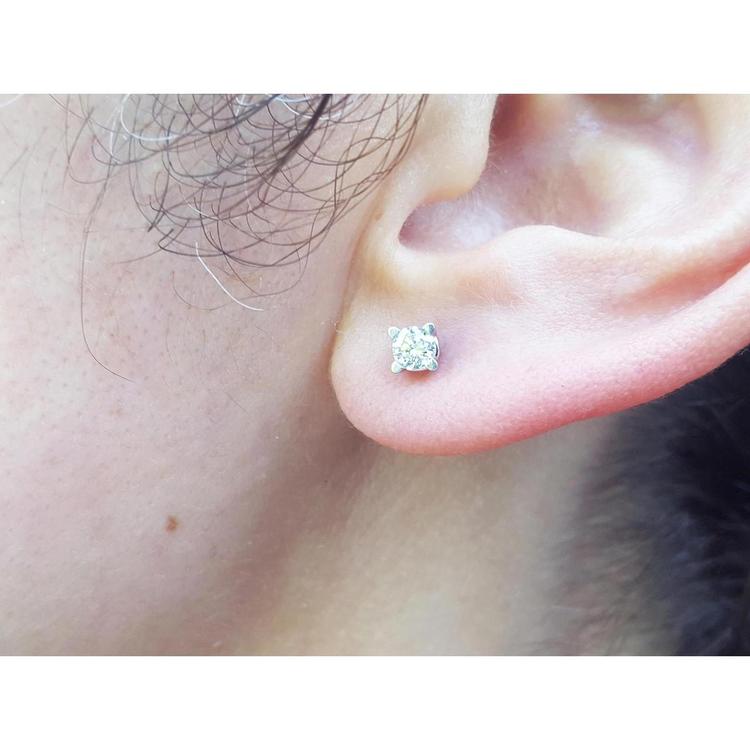 A woman's ear dressing a natural diamond stud earring screw back.