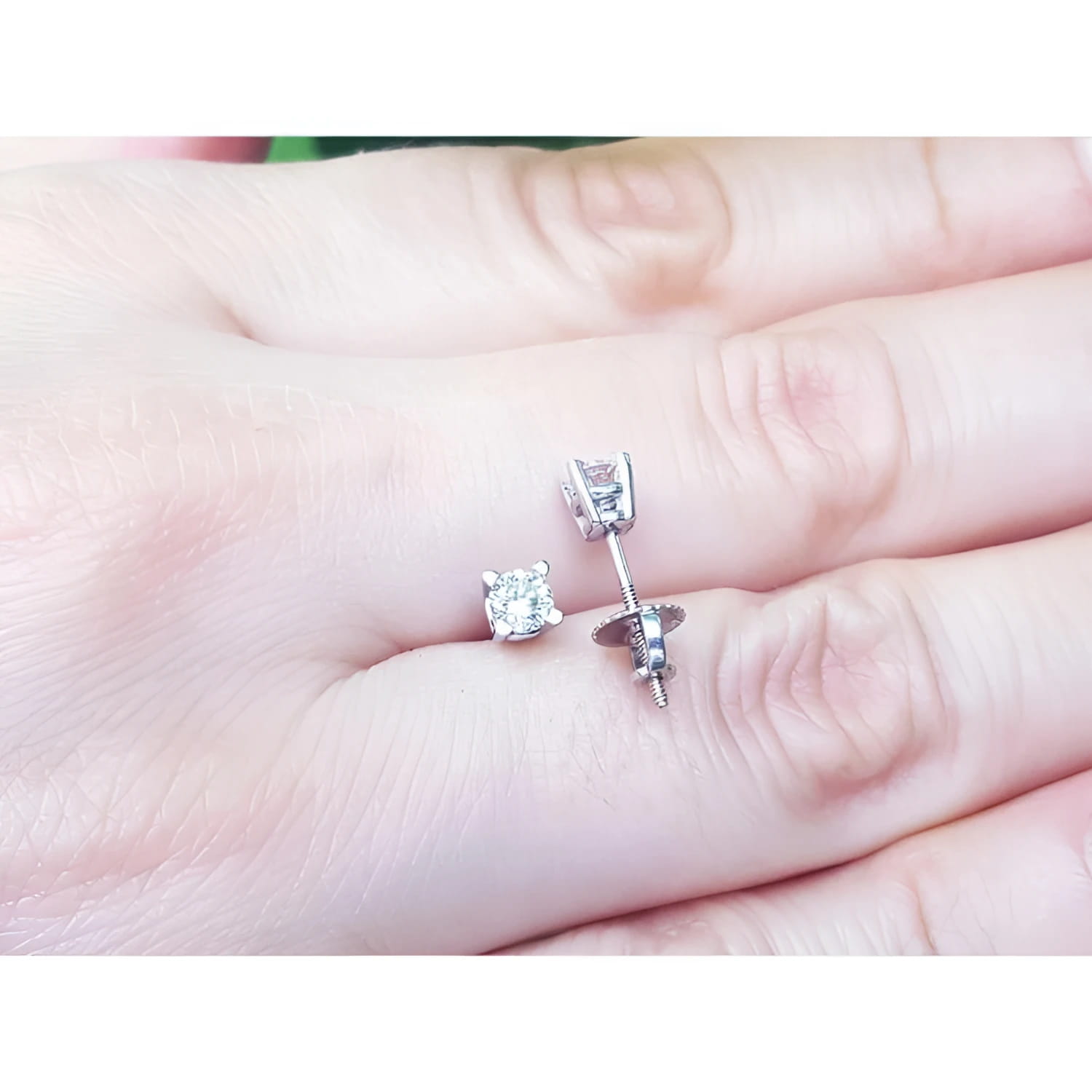 0.46 ct natural diamond stud earrings with screw backs, set in 14K white gold on a hand.