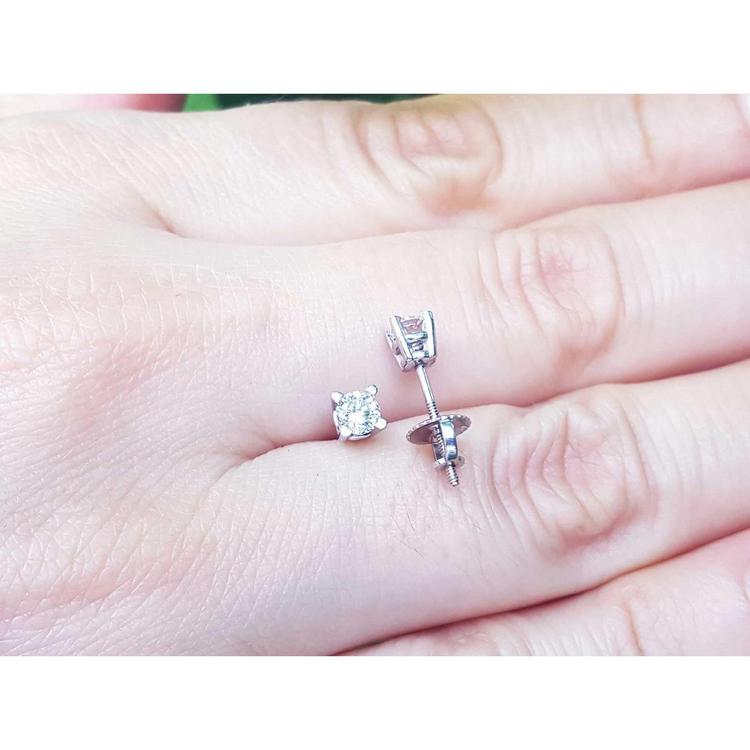 On a hand displaying a screw backs natural diamond stud earrings white gold.