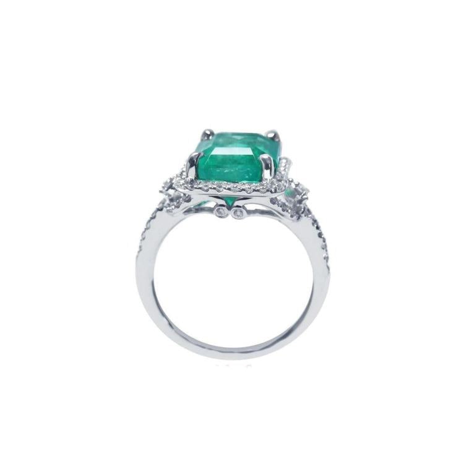 Emerald-cut natural Colombian emerald ring with diamond halo and 14k white gold band.