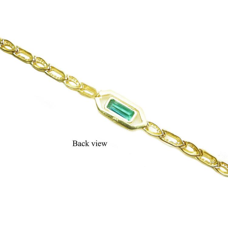 The back side view of a gold bracelet with a rectangular emerald on a white background