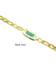 The back side view of a gold bracelet with a rectangular emerald on a white background