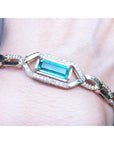 Gold bracelet with a rectangular natural colombian emerald and diamonds on a wrist.