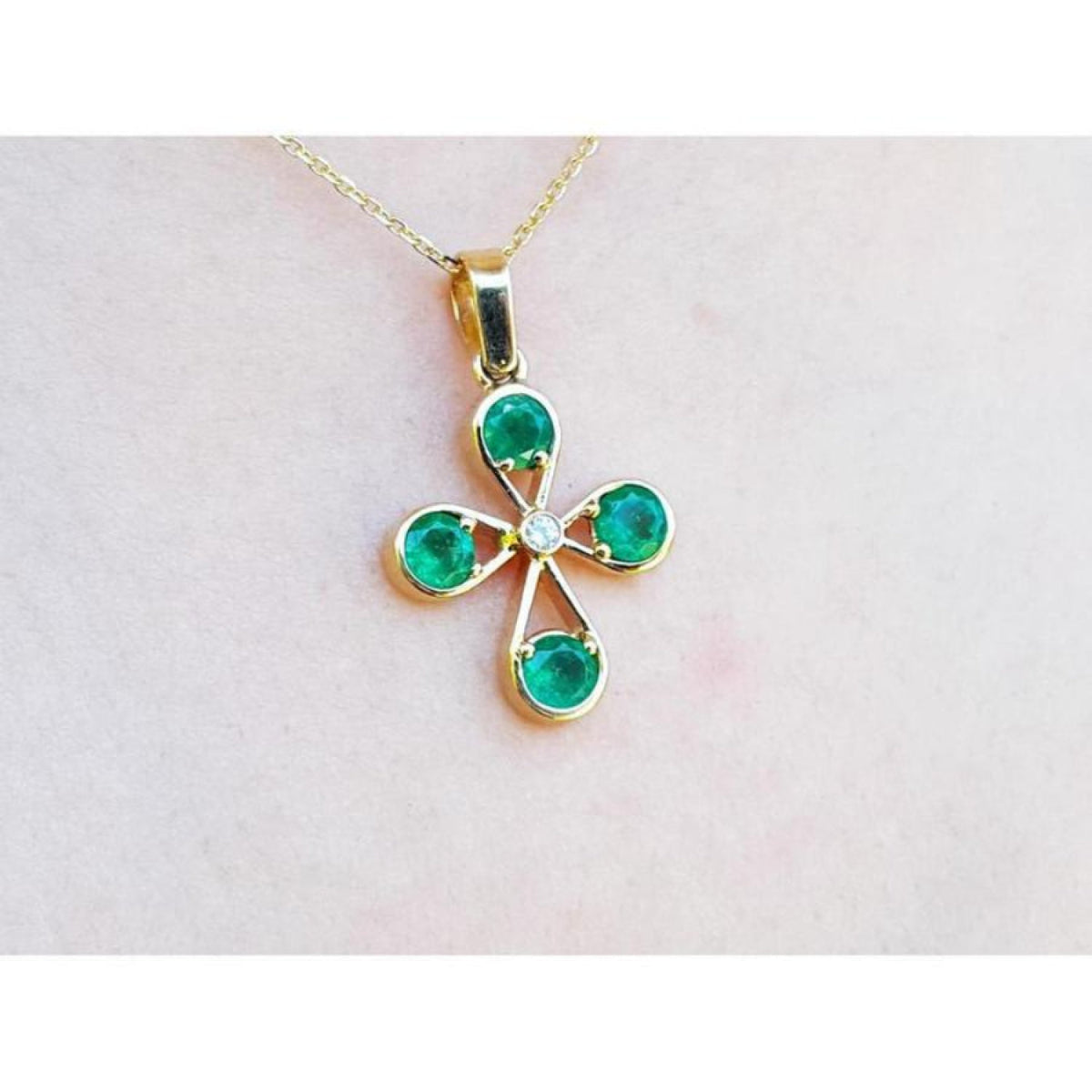 18K yellow gold cross pendant with four round Colombian emeralds and a central diamond.