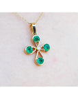 18K yellow gold cross pendant with four round Colombian emeralds and a central diamond.