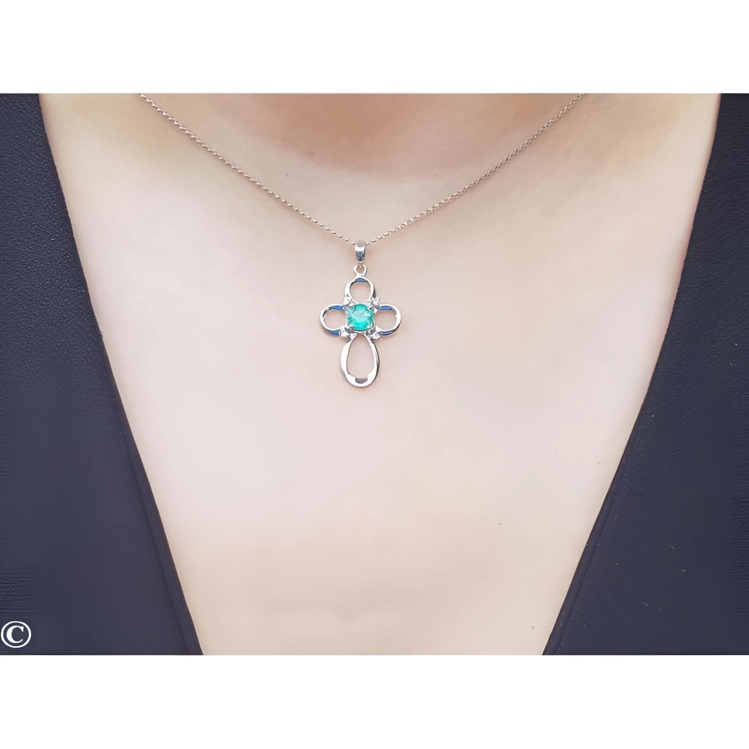 14K white gold cross pendant with a round Colombian emerald and diamond accents on a delicate chain.
