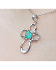 A 14k white gold emerald cross pendant on a chain, worn on a person's neck.