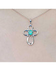 14K white gold cross pendant with a round Colombian emerald and diamond accents on a chain.