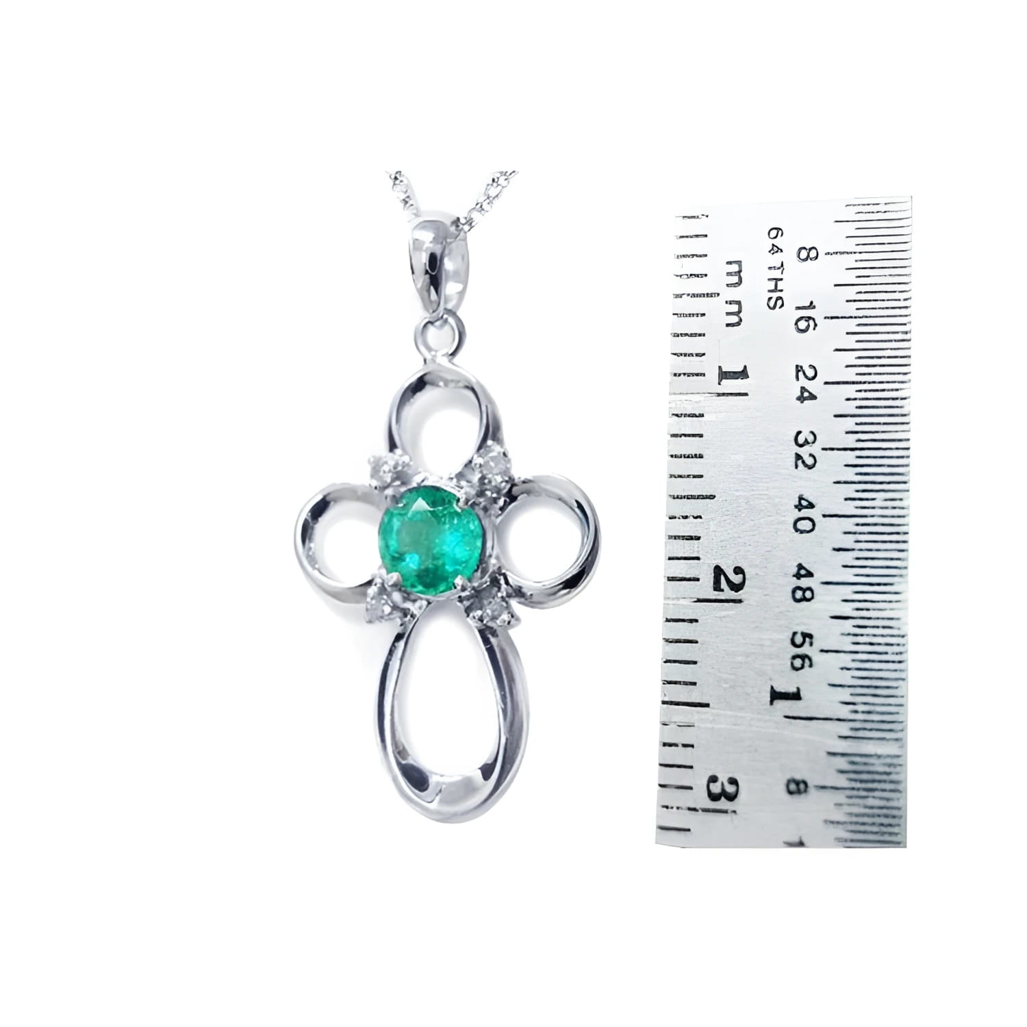 14K white gold cross pendant with a round green Colombian emerald and diamond accents, next to a ruler.