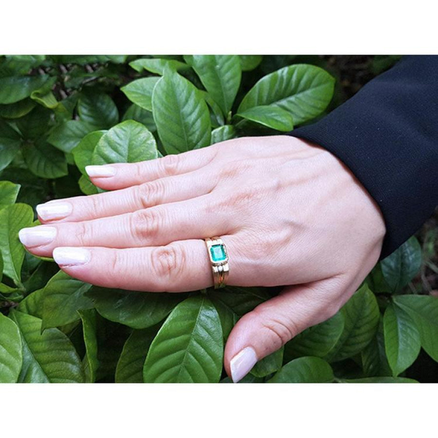 Men's 14K yellow gold ring with a bezel-set natural emerald and diamond accents on a hand.