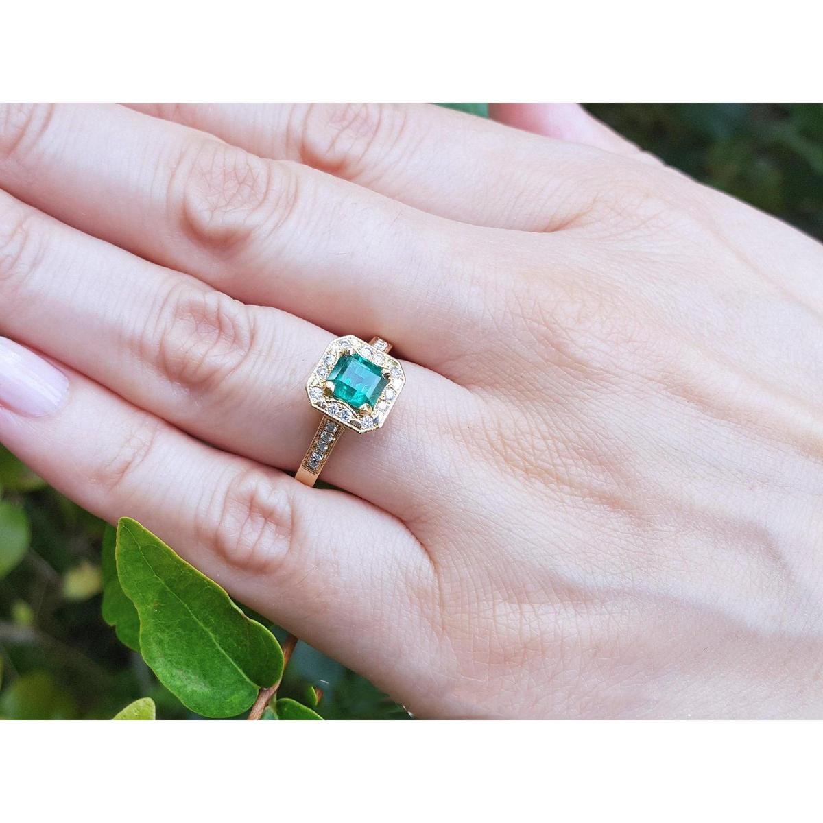 A May's birthstone emerald ring for women on a hand against a natural background.