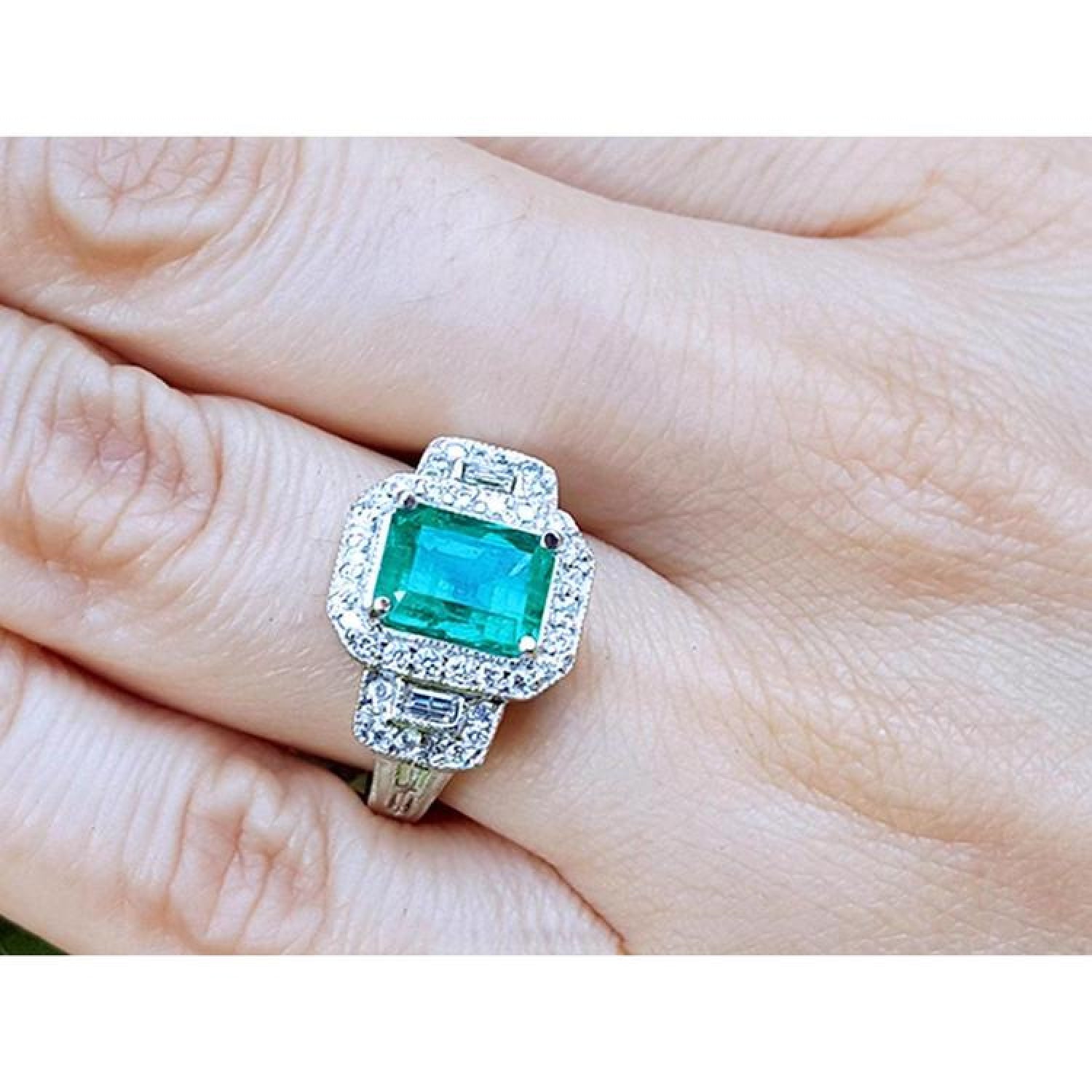 2.47 ct. GIA certified F1 emerald engagement ring in 18K white gold with diamond halo and baguette side diamonds.