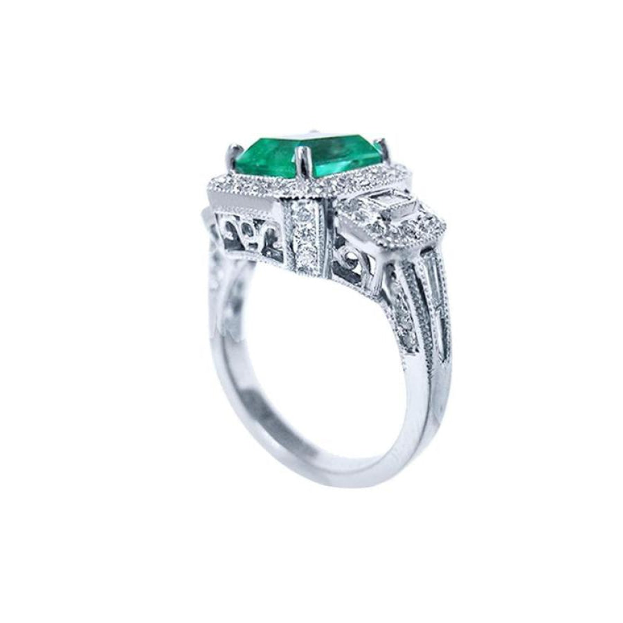 18K white gold engagement ring with a vibrant emerald, diamond halo, and baguette side diamonds.