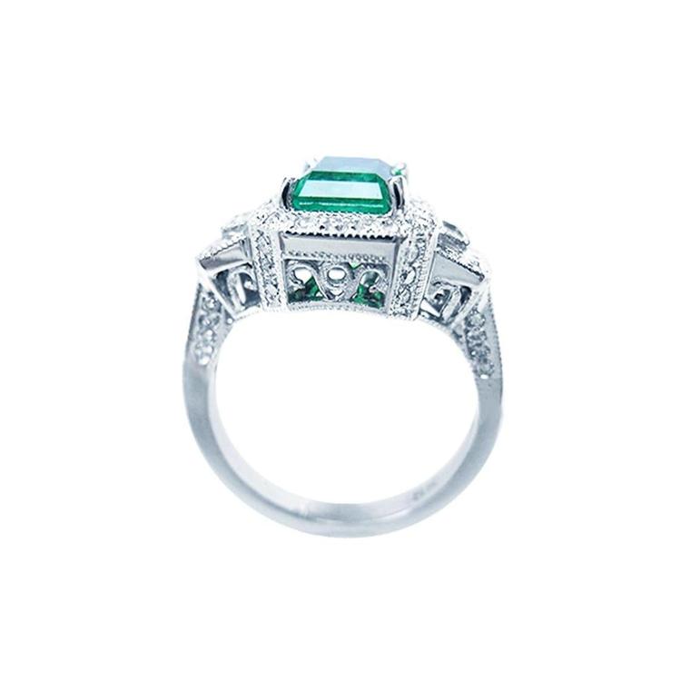 18K white gold engagement ring with a vibrant emerald, diamond halo, and baguette side diamonds.