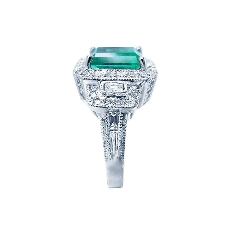 Vibrant 2.47 ct. emerald engagement ring in 18K white gold with diamond halo and baguette side diamonds.