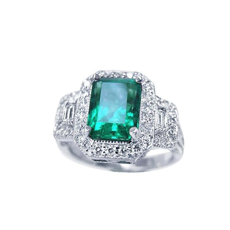 This natural colombian emerald engagement ring is adorned with a halo of natural diamonds and made of 18k white gold.