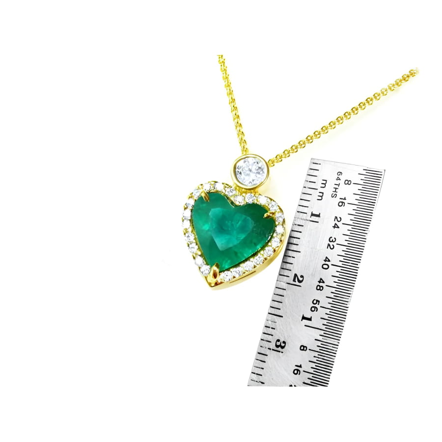 18k gold heart pendant with a large bluish-green emerald, halo diamonds, and a delicate gold chain.