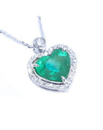 Heart-shaped natural emerald pendant with halo diamond accents made of 14k white gold.