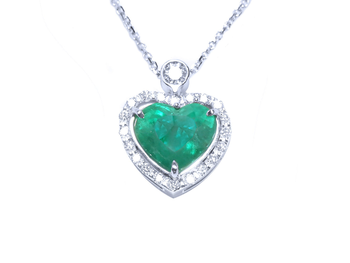 Heart-shaped emerald pendant on a topside view front position, halo diamond visible.