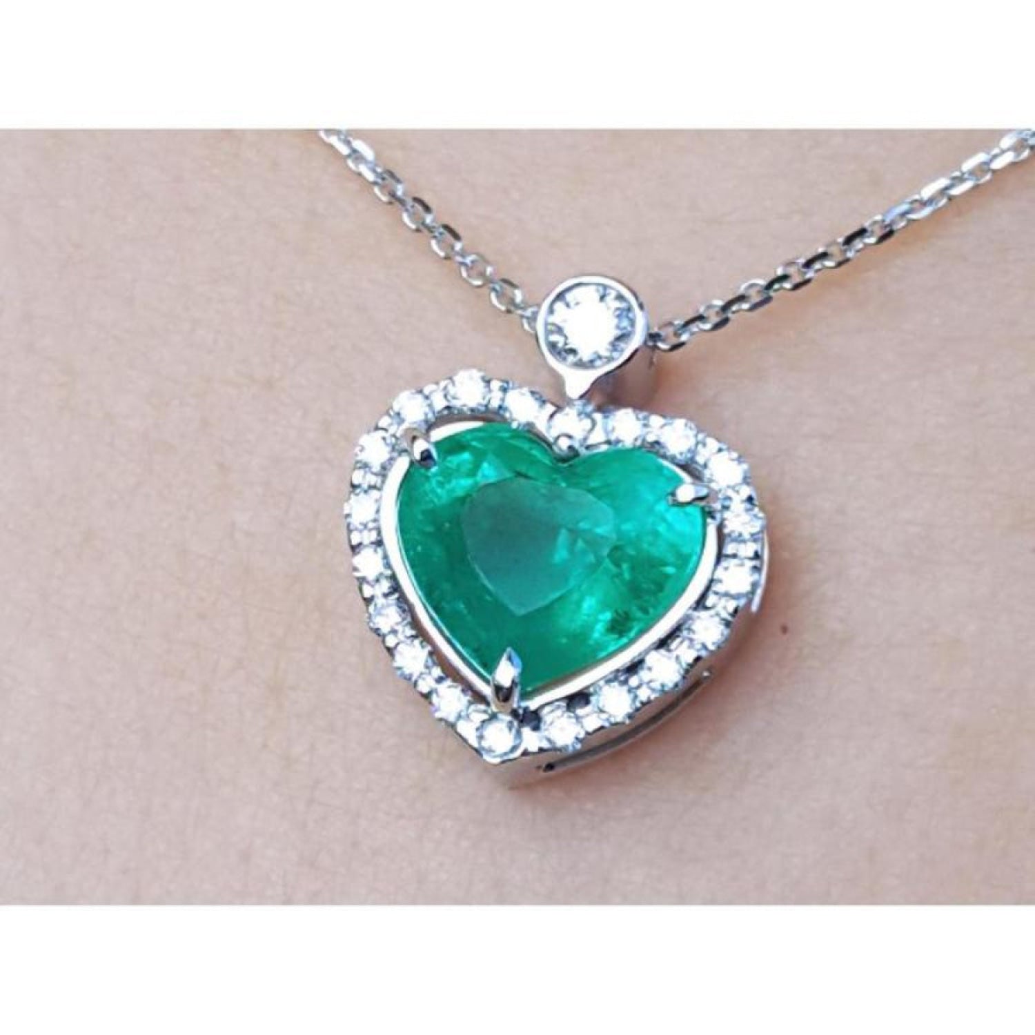 Heart-shaped emerald pendant with diamond accents on a white gold chain.