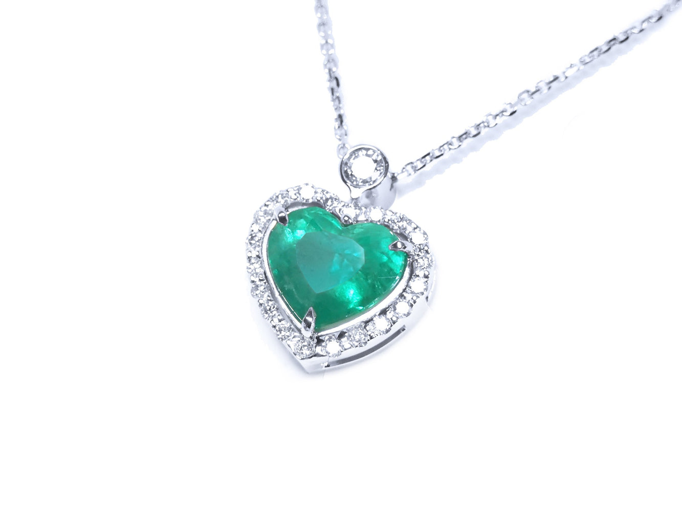 Heart-shaped emerald pendant with diamond accents on a topside left profile position.