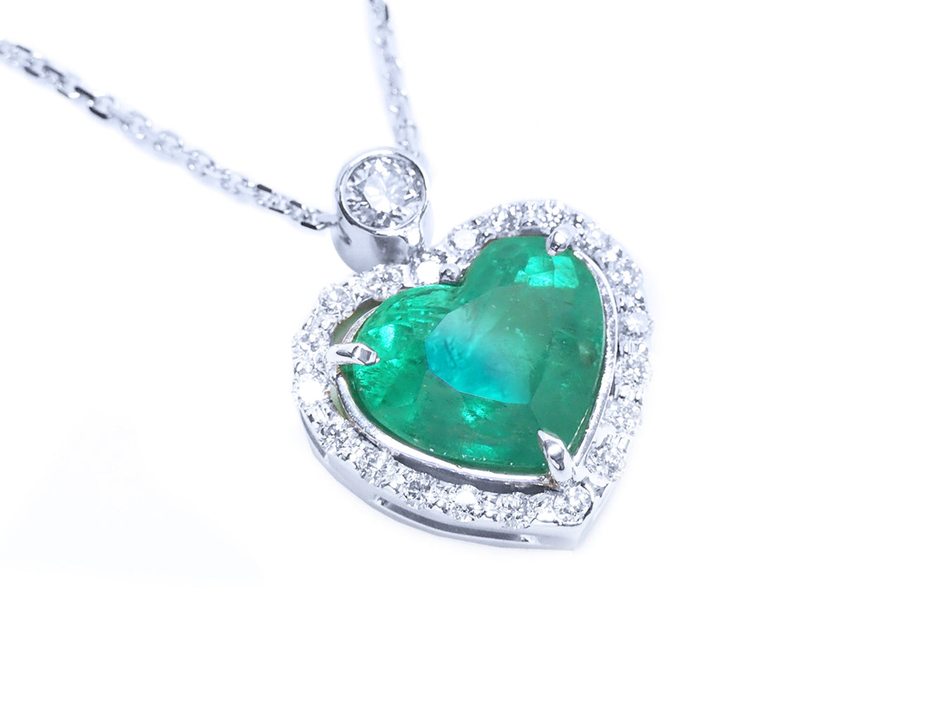 Heart-shaped emerald pendant with diamond accents on a toside view position