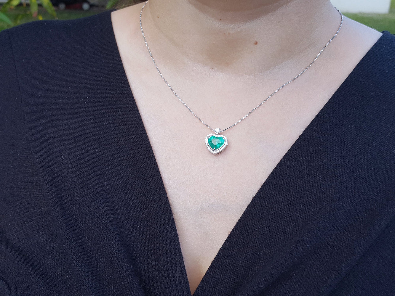 Necklace with a heart-shaped pendant worn by a woman in a dark blue outfit.