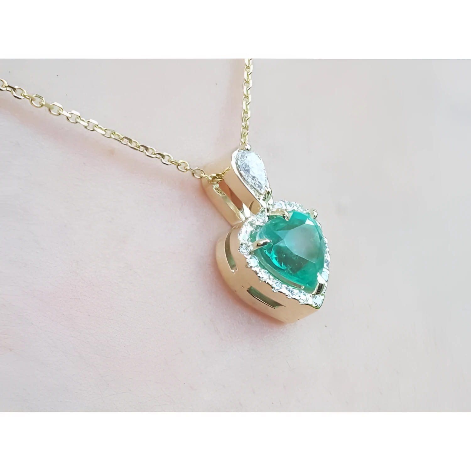 14K yellow gold heart pendant with a medium-deep green emerald and diamond halo on a delicate chain.